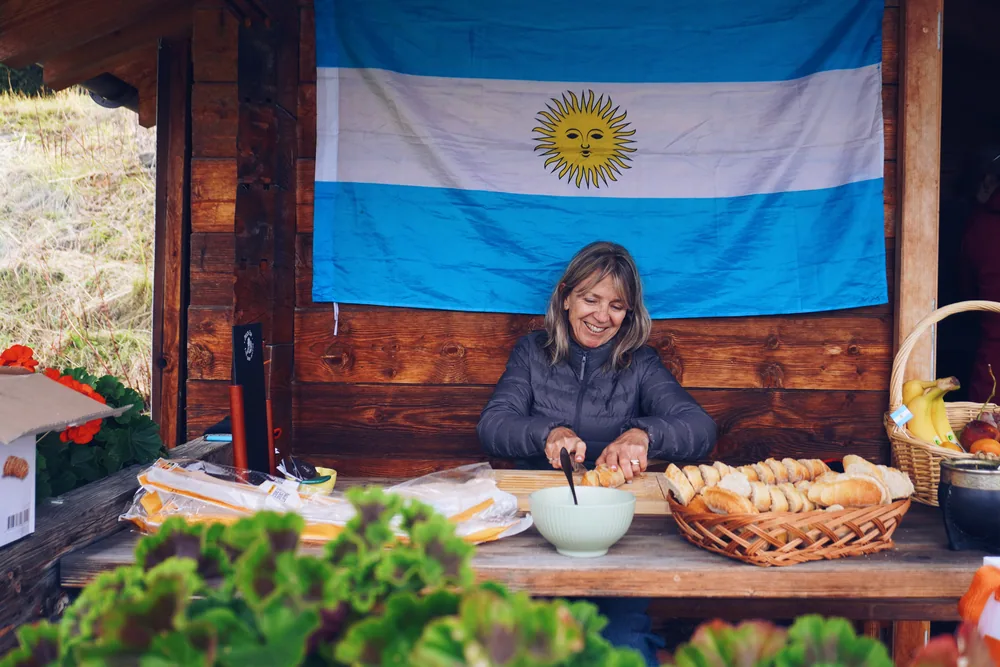 Claudia cutting bread under an Argentine flag at the golf club