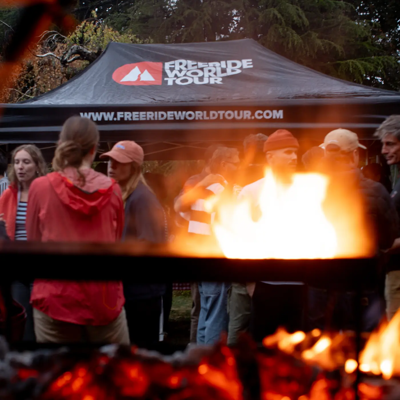 Guests around the fire under the Freeride World Tour tent