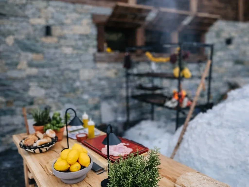 A long table set with lemons and rosemary next to the asador, snow on the ground