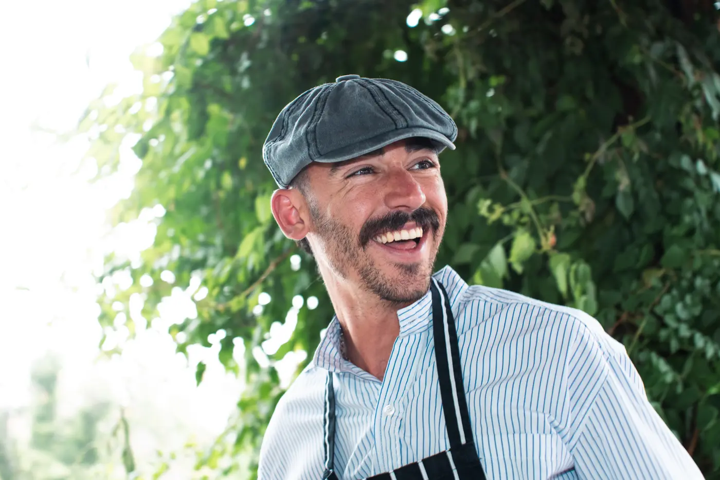 Octa laughing by the grill, cap and apron on