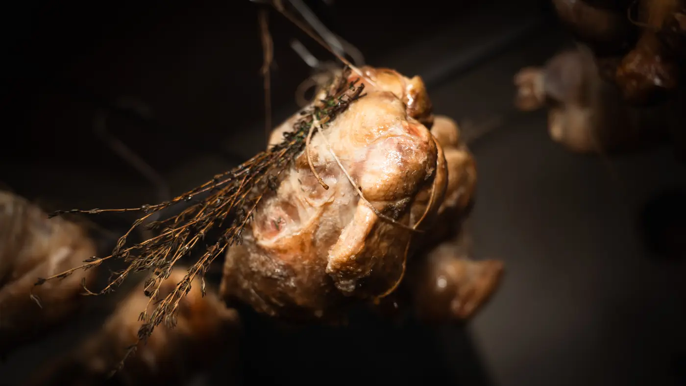 A chicken hanging over the fire, tied up with herbs