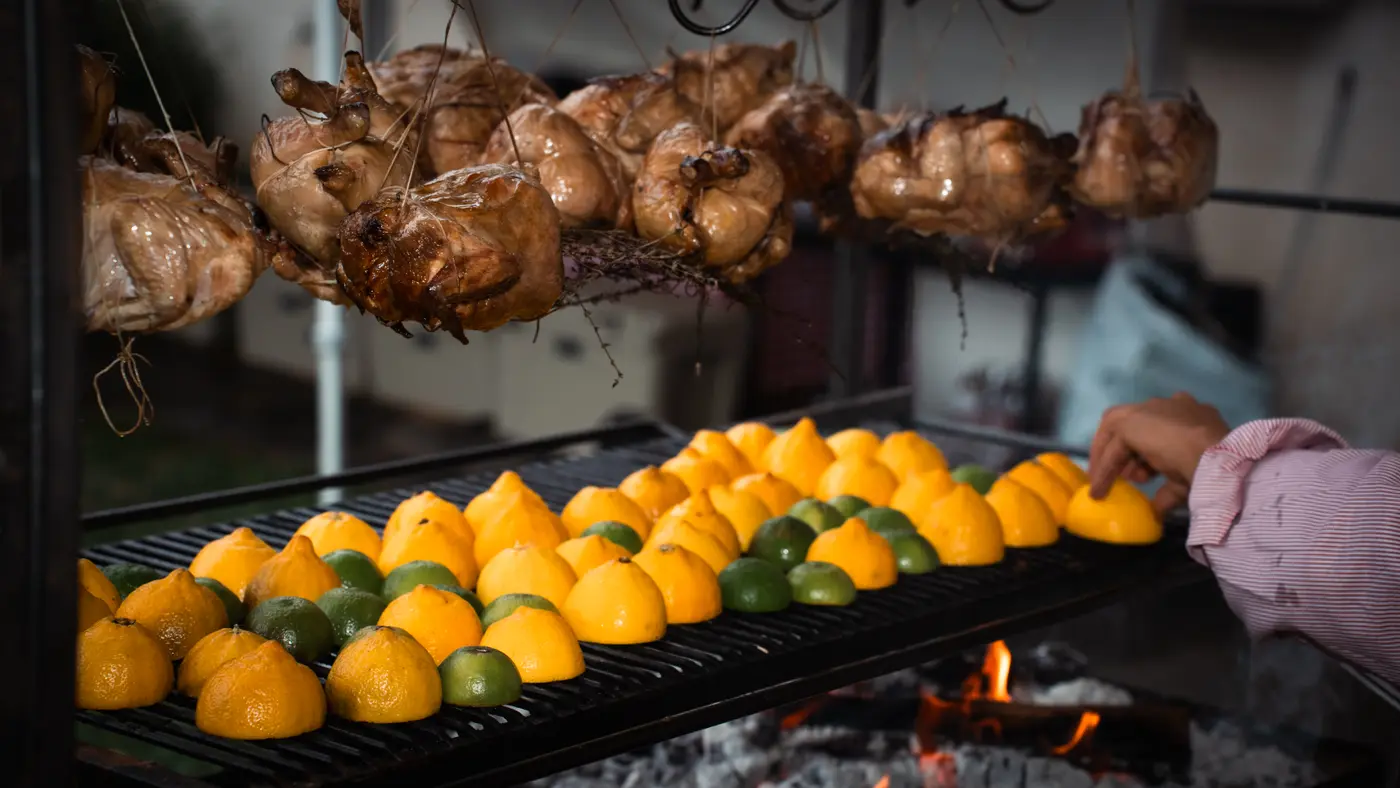 Lemon halves on the grill, chickens hanging above