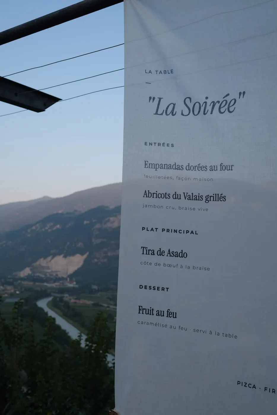 The printed menu hanging, the valley behind it