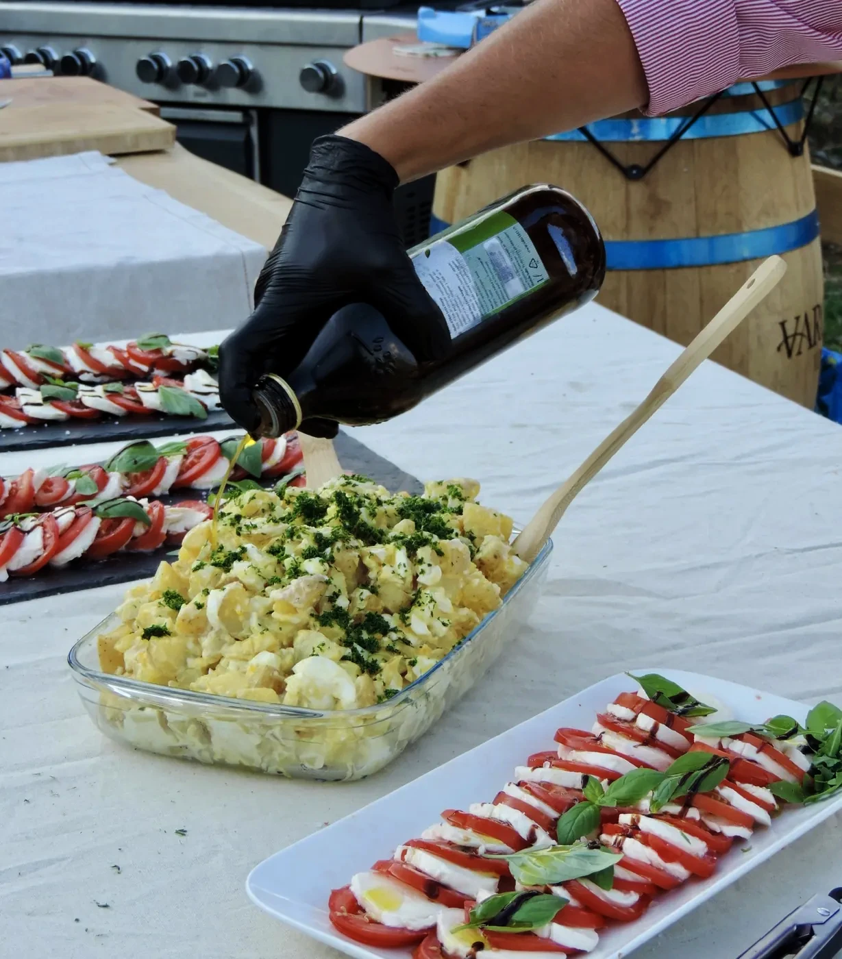 A gloved hand dressing the salads laid out on the table