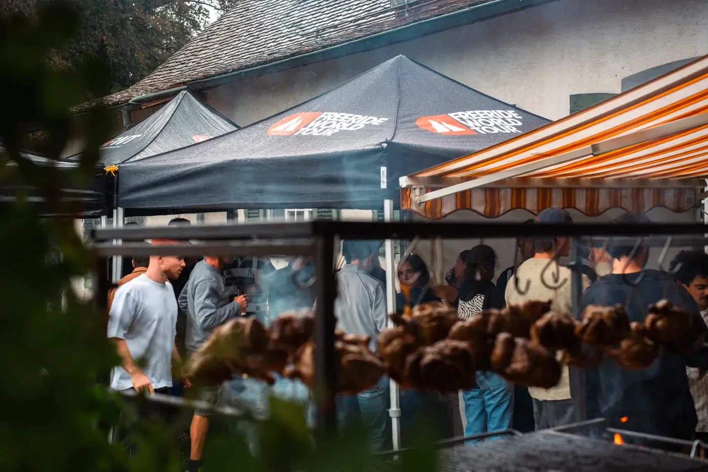 Guests under the Freeride World Tour tents, chickens hanging over the fire
