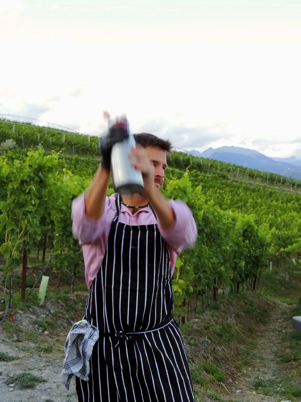 A shaker held high against the sky, apron on